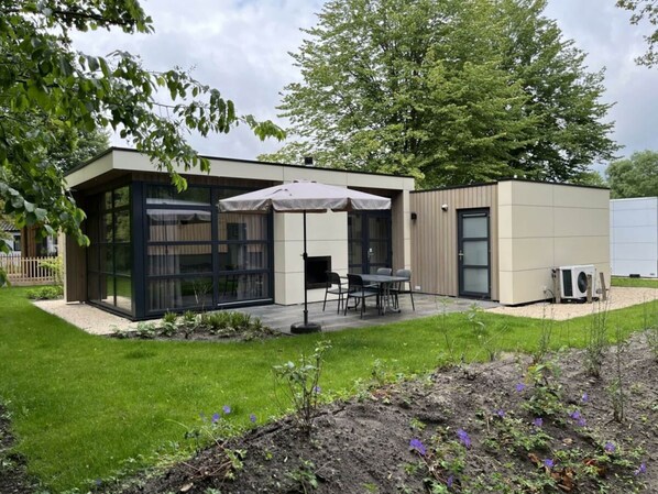 A modern building with large glass windows, a patio with outdoor seating, and a small garden area. - Holiday Home in Velsen-zuid With Terrace (Velsen-Zuid)