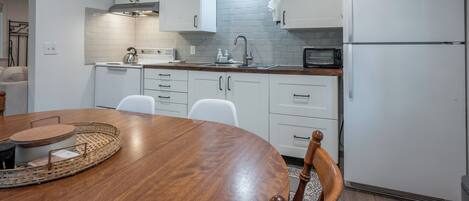 Eine moderne Küche mit weißen Schränken, einem Holztisch und einem eingebauten Ofen.