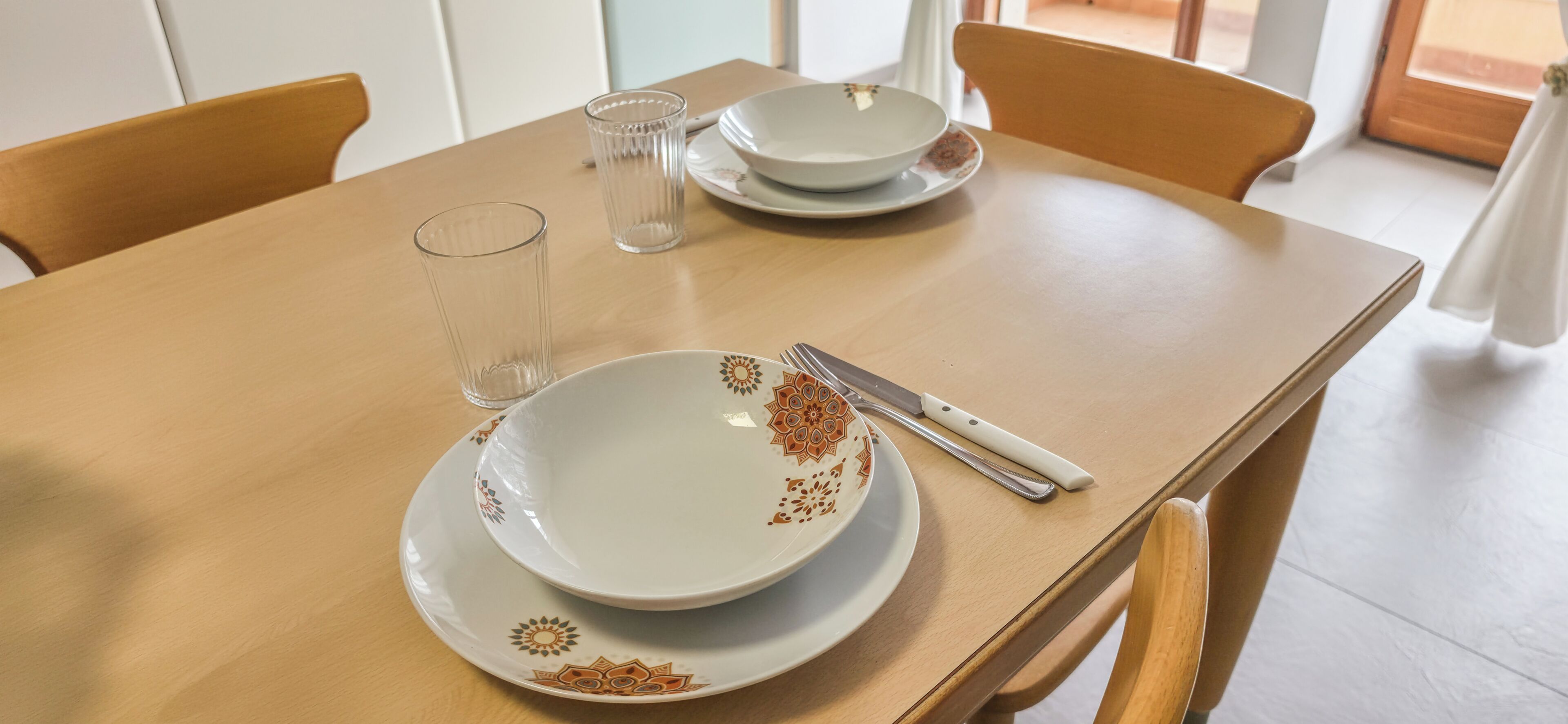 Una mesa de comedor con platos, un vaso y un cuchillo.