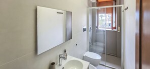 Ein Badezimmer mit Spiegel, Waschbecken, Toilette und Duschkabine.
