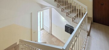 A multi-level interior with a staircase, a door, and a vent on the wall.