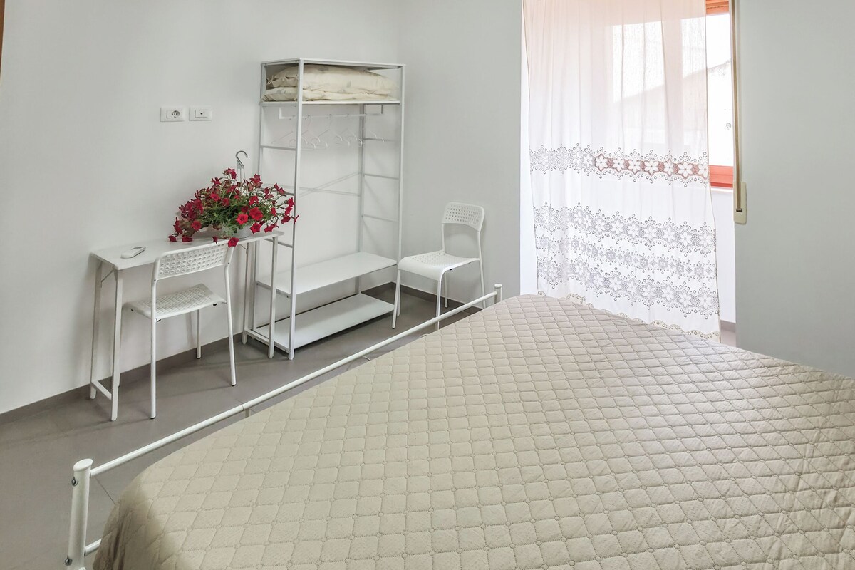 Un dormitorio con cama, un escritorio con silla, un armario y una ventana con cortina.