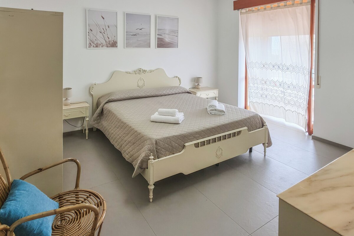 Un dormitorio con cama, una silla, una mesa y un armario.