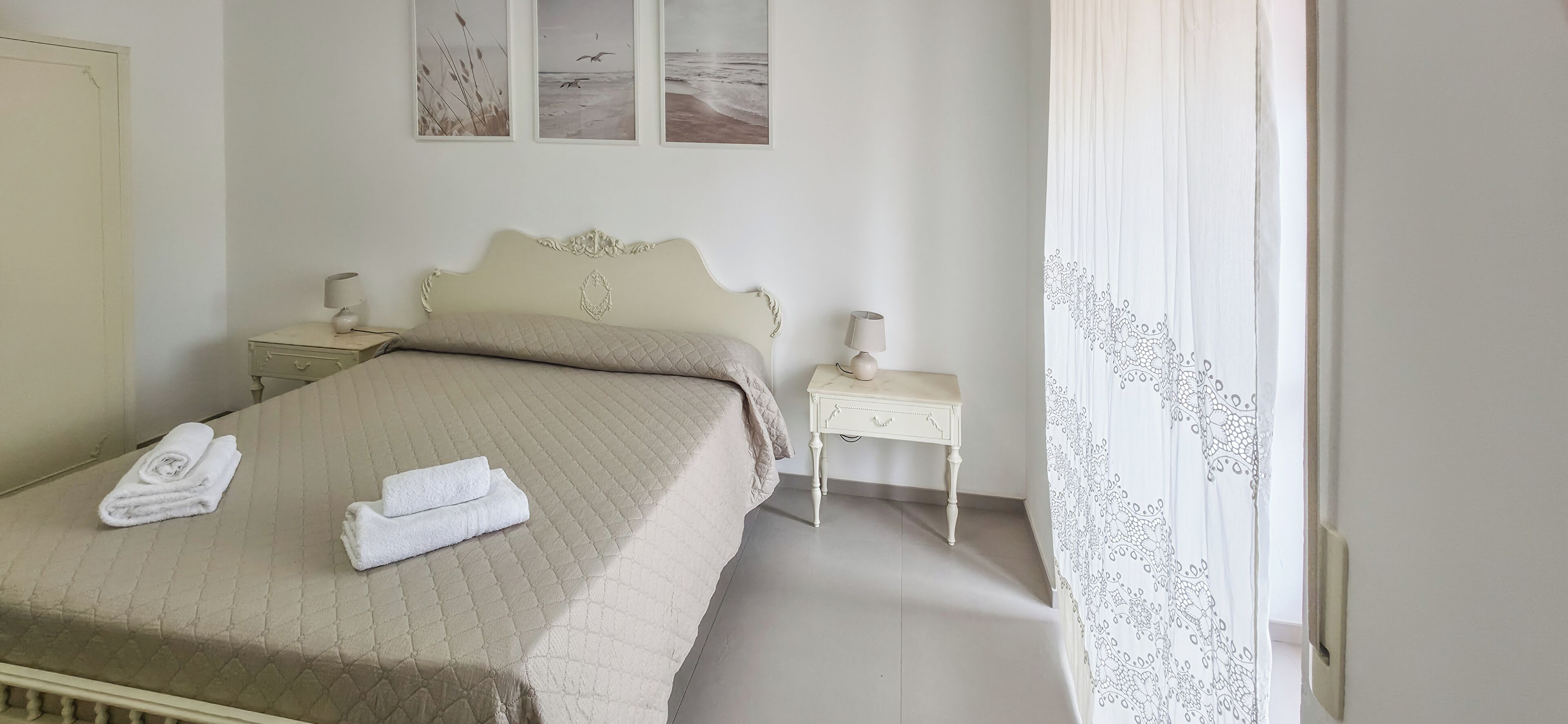 Un lit bien fait avec deux serviettes, une table de chevet avec une lampe et une petite table de nuit avec une lampe.