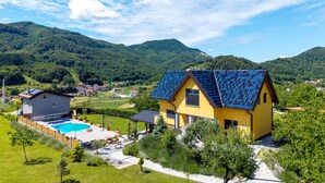 Una casa gialla con un tetto solare, una piscina e un giardino.