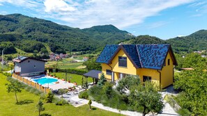 Ein gelbes Haus mit einer Solaranlage auf dem Dach, einem Swimmingpool und einem Garten.