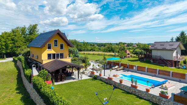 Una proprietà residenziale con piscina, patio coperto e muro in pietra.