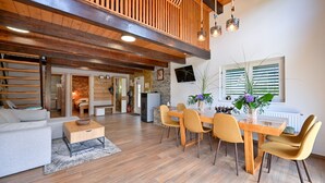 Un interno moderno con zona pranzo, soffitto in legno e cucina visibile sullo sfondo.