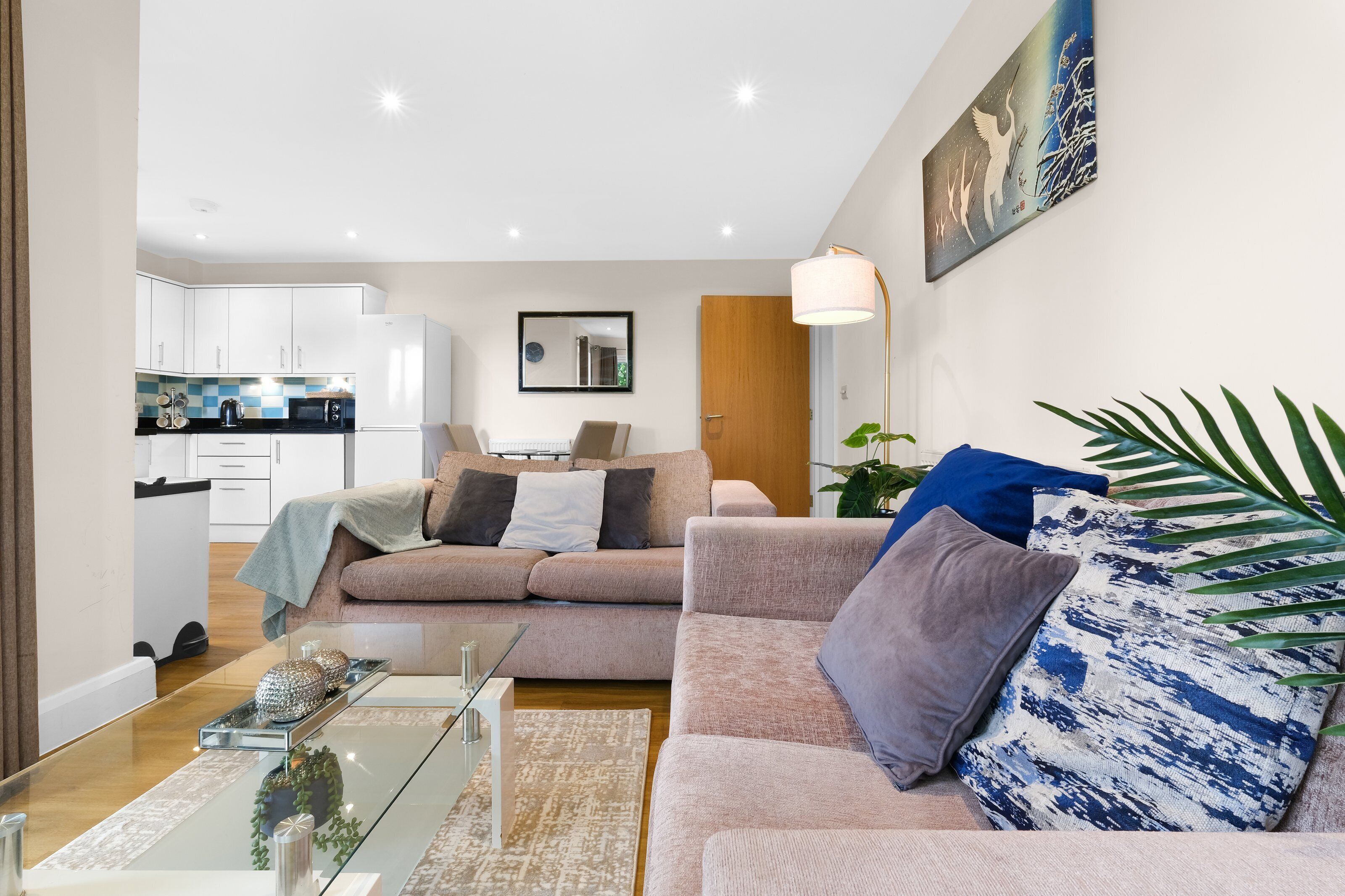 Ein modernes Wohnzimmer mit Sofa, Couchtisch und Blick in die Küche.