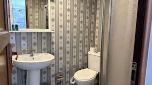 Casa de banho com uma sanita, lavatório branco e um espelho sobre o lavatório.