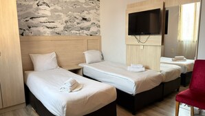 Quarto de hotel com duas camas, uma TV fixada na parede e uma cadeira vermelha.