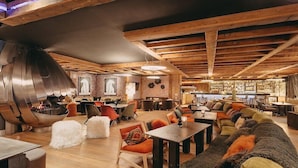 A spacious lounge area with wooden beams, a fireplace, and comfortable seating.