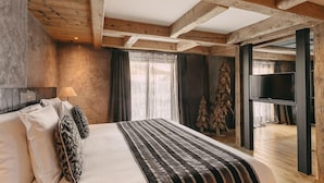 A bedroom with a bed, pillows, a TV, a window, and a wooden ceiling.