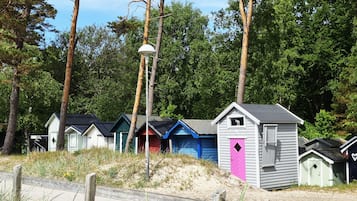 En rad strandhytter med tak i olika färger och en lyktstolpe i förgrunden.