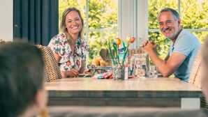 A dining table with a wicker chair, a glass pitcher, and a bottle of CoolDry. - Holiday Home in Susteren With Terrace (Susteren)