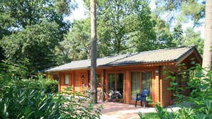 A wooden cabin with a porch, bicycles, and a number 134 sign. - Holiday Home in Susteren With Terrace (Susteren)