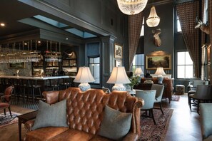 Uma área de bar com balcão, banquetas e um candelabro.