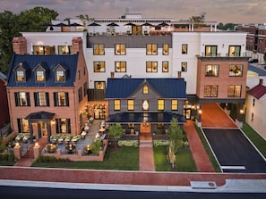 A multi-story hotel with a courtyard, outdoor seating, and a mix of architectural styles. - Downtown Leesburg | Rooftop Bar + Wine Country (Leesburg)