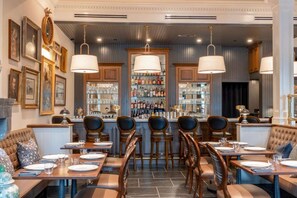 A restaurant with a bar area, multiple seating options including booths and tables, and a variety of framed artwork on the walls. - Historic Leesburg Stay | Fitness Center + Sauna (Leesburg)