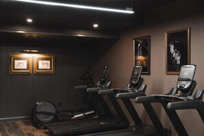 A gym with treadmills, stationary bikes, and a rowing machine. There are framed pictures on the wall. - Near Top Wineries | Pet Friendly, Sauna + Dining (Leesburg)