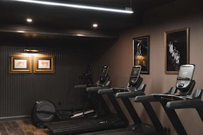 A gym with treadmills, stationary bikes, and a rowing machine. There are framed pictures on the wall. - Leesburg Luxury Stay with Dining + Pets Stay Free (Leesburg)
