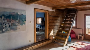 A rustic room with a wooden staircase, a painting on the wall, and a view into another room. - Holiday Home for 9 Guests, 200 m², with Balcony and Wi-Fi (Rettenschöss)