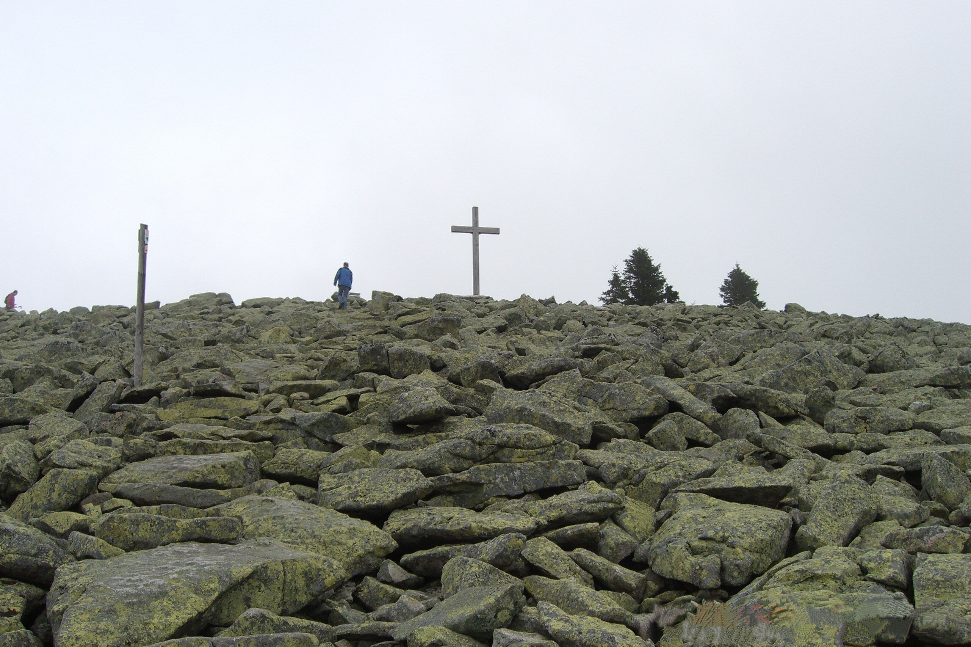 Terreno rocoso con una cruz y algunas personas.