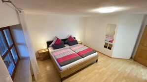 Een slaapkamer met een houten bed, nachtkastjes, een spiegel en een raam.