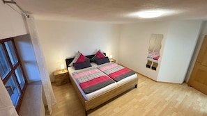 Ein Schlafzimmer mit Bett, Nachttischen, einem Spiegel und Holzboden.