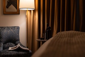 A hotel room with a bed, a chair, a lamp, a bottle, and a glass on a small table. - Close to Wineries + Pet Friendly & On Site Dining (Leesburg)