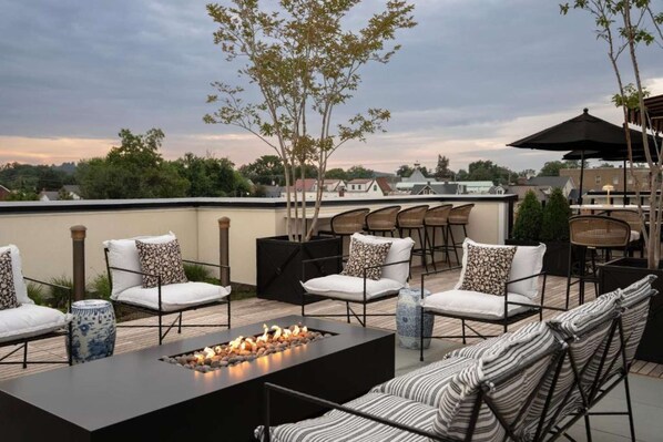A rooftop patio with outdoor seating, a fire feature, and a view of the cityscape. - Close to Wineries + Sauna & On Site Dining (Leesburg)