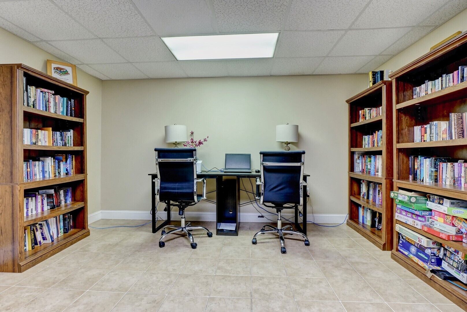Une bibliothèque avec deux bureaux, des chaises et des étagères remplies de livres.