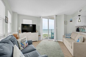 Ein Wohnzimmer mit Fernseher, einer Couch und einem Balkon mit Blick.