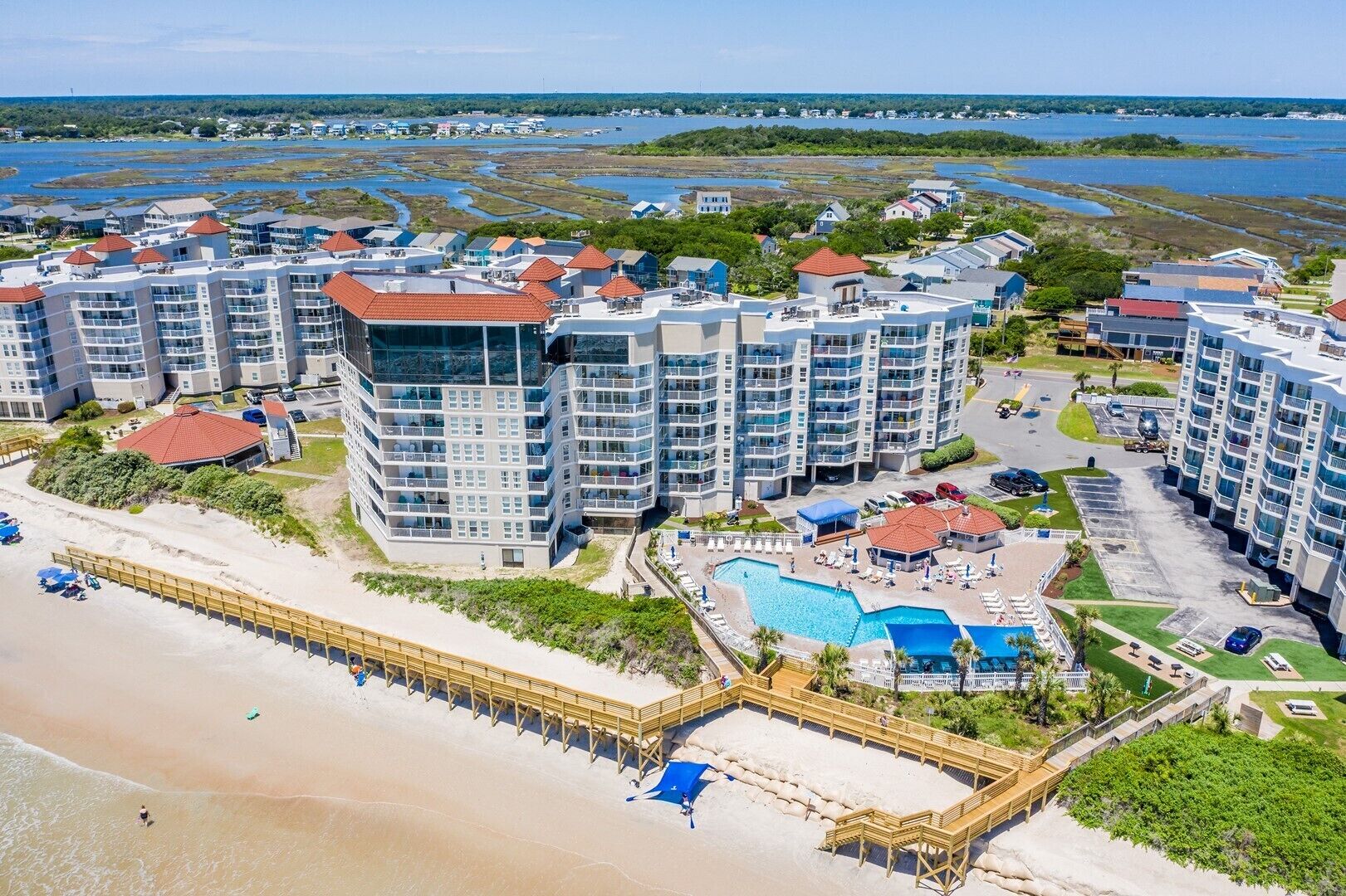 Un hotel costero con varios edificios altos, una playa y una piscina.