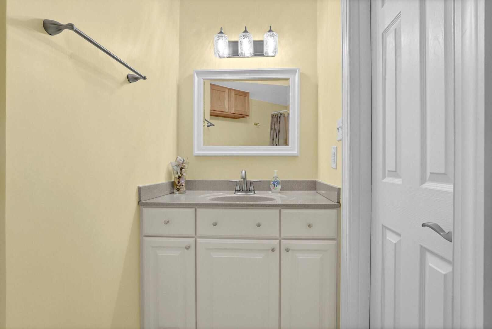 A bathroom with a sink, mirror, and towel rack.