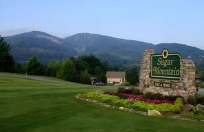 Placa de Sugar Mountain com campo de golfe e quadra de tênis, rodeada por vegetação e montanhas.