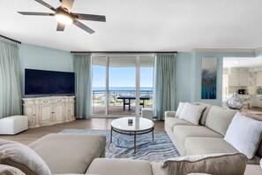 A living room with a television, sofa, and a view of the ocean.