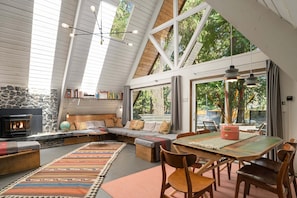 Ein gemütliches Interieur mit Kamin aus Stein, Holzboden und einer Essecke mit Tisch und Stühlen.