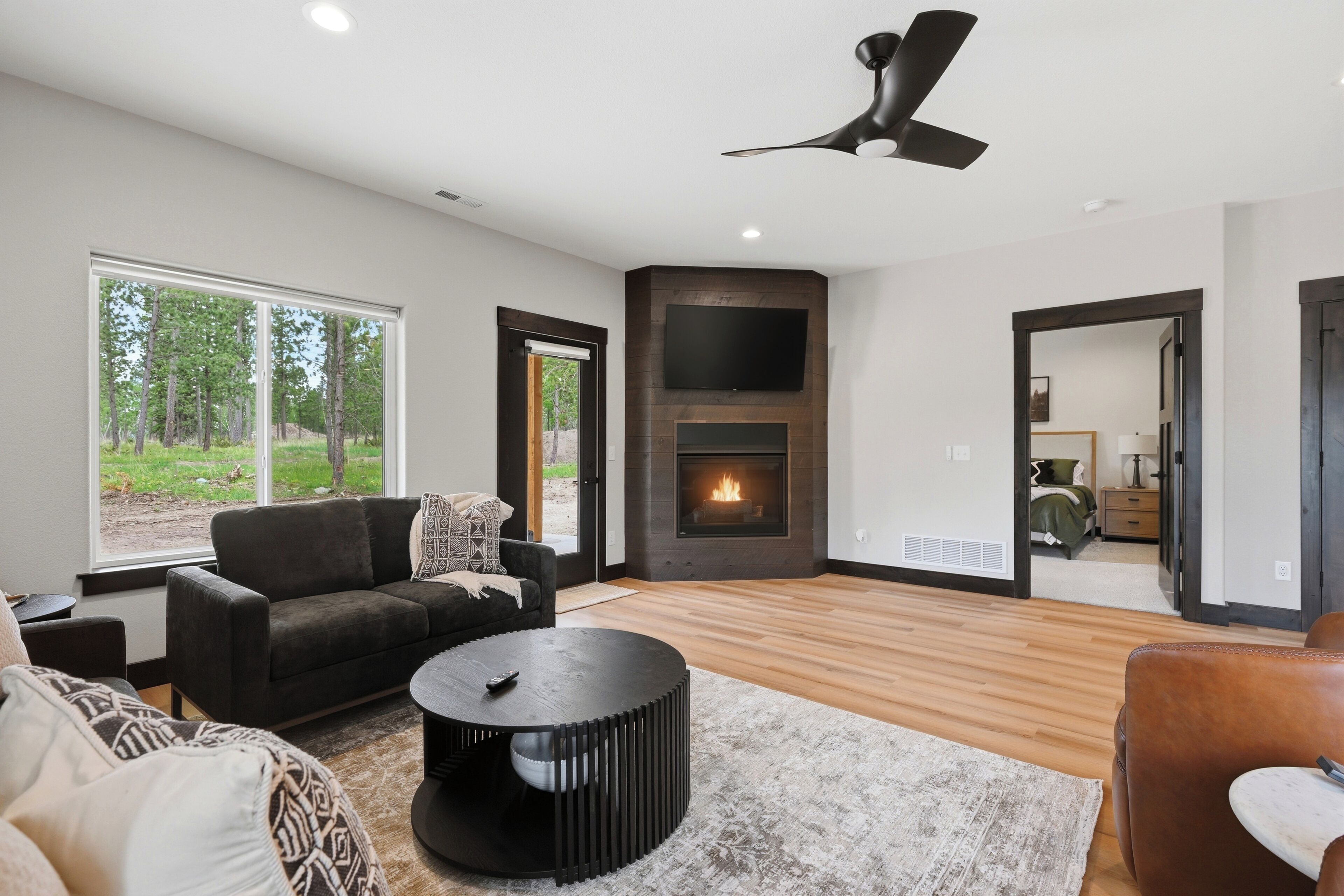 Un salon moderne doté d’une cheminée, d’une grande fenêtre et d’un ventilateur de plafond.