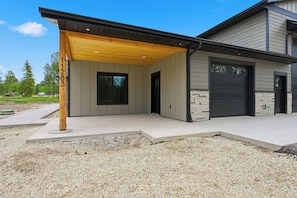 A modern house with a covered porch, a garage, and a stone facade.