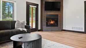 A modern living room with a fireplace, a sofa, and a TV mounted on the wall.