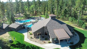 A large house with a swimming pool, surrounded by a well-maintained lawn and trees.