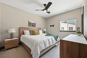 A bedroom with a bed, bedside tables, a ceiling fan, a window, and a desk area. - Upscale Property w/ Giant Garage and Mezzanine Entertaining Space! (Lead)