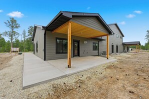 A modern two-story house with a covered porch, a driveway, and a gravel yard.