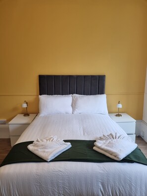 A hotel room with a bed, two bedside tables, and a nightstand. - Two-Bedroom Suite (Sheffield)