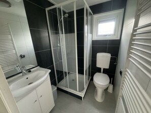 Een badkamer met een douchecabine, toilet en wastafel.