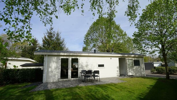 A single-story building with a patio area, a table with chairs, and a covered outdoor seating area. - Holiday Home in Susteren With Sauna (Susteren)