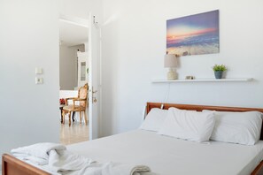 Ein ordentlich bezogenes Bett mit weißen Leinen, einem hölzernen Kopfteil und einer Wandlampe.