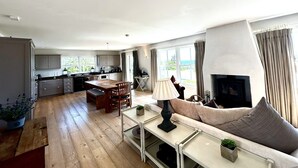Ein geräumiger Wohnbereich mit einer Couch, einem Esstisch und einer Küche im Hintergrund.