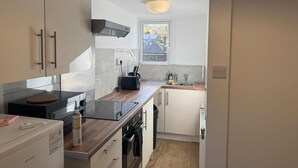 Et moderne køkken med indbygget komfur, ovn og mikroovn. Et vindue giver naturligt lys og udsigt udad.